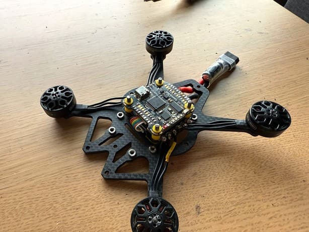 Top-down view of a carbon fiber quadcopter frame with ESC stack and motors wired