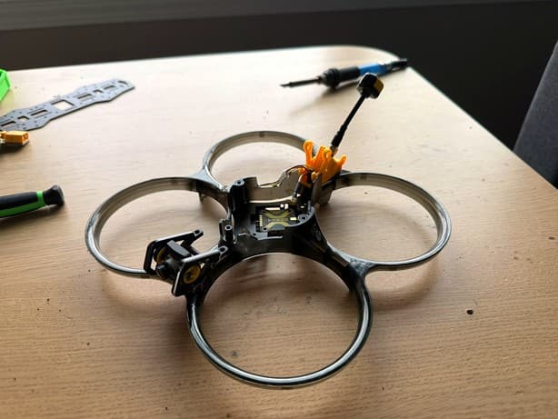 Translucent ducted cinewhoop frame with camera and VTX antenna on a workbench